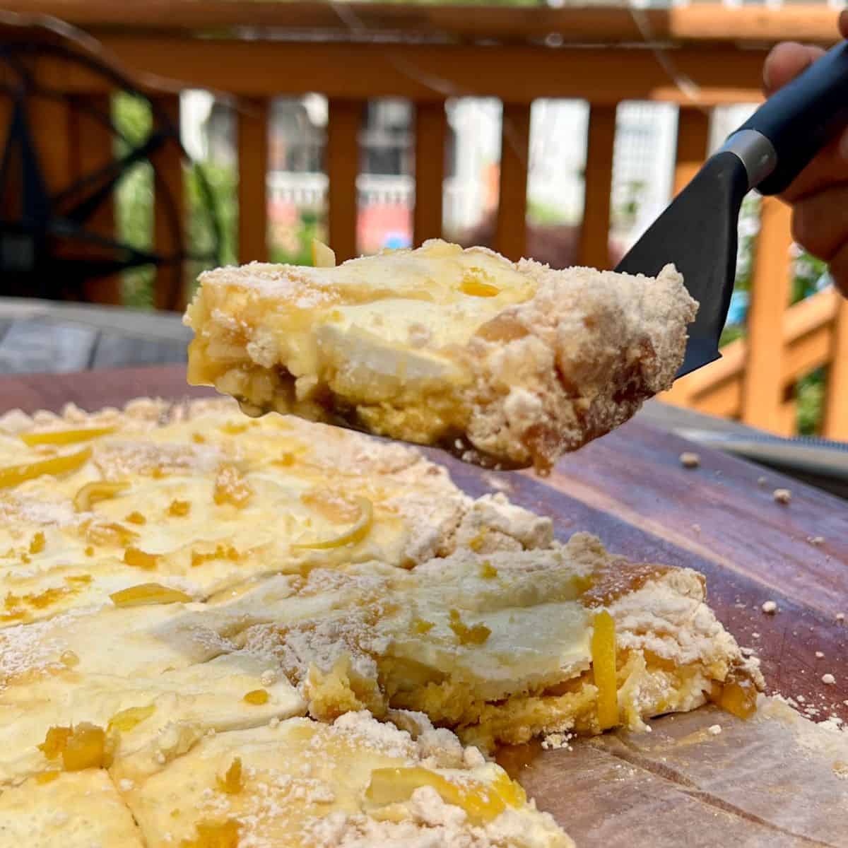 A slice of 4 ingredient lemon dump cake on a spatula over a lemon dump cake