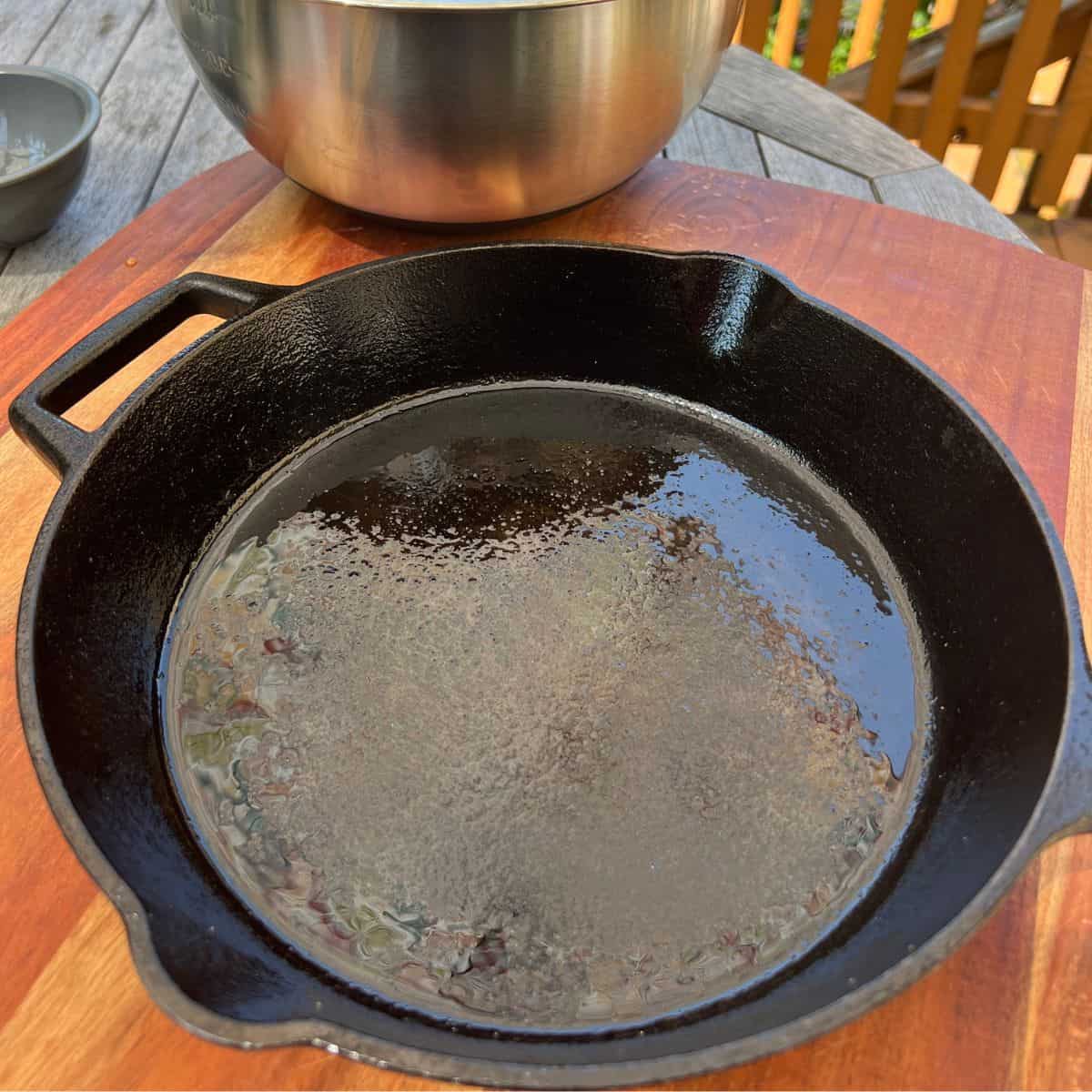 A greased cast iron skillet for baking a peach cobbler dump cake
