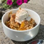 Peach Cobbler Dump Cake in a white bowl with vanilla ice cream