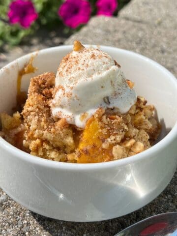 Peach Cobbler Dump Cake in a white bowl with vanilla ice cream