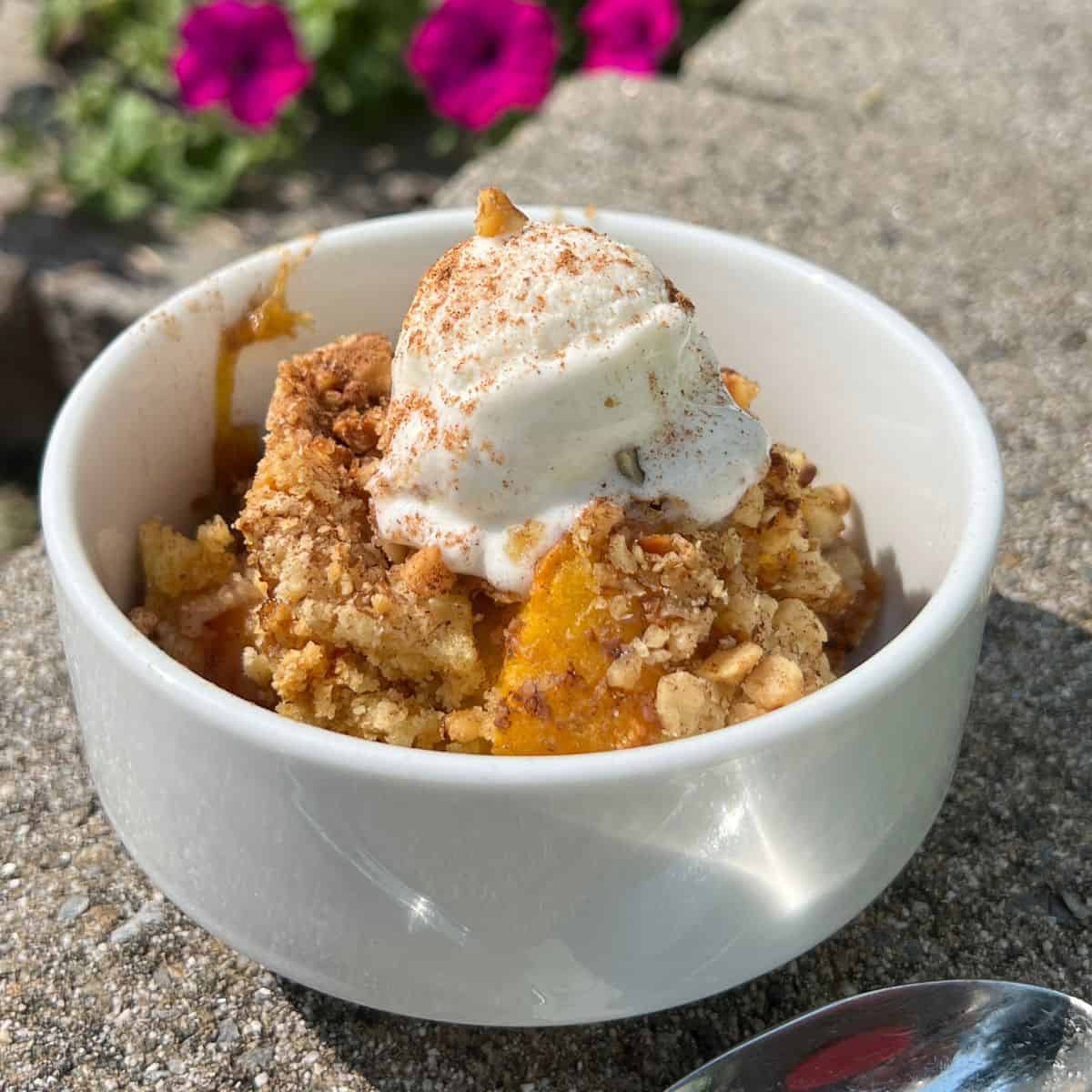 Peach Cobbler Dump Cake in a white bowl with vanilla ice cream
