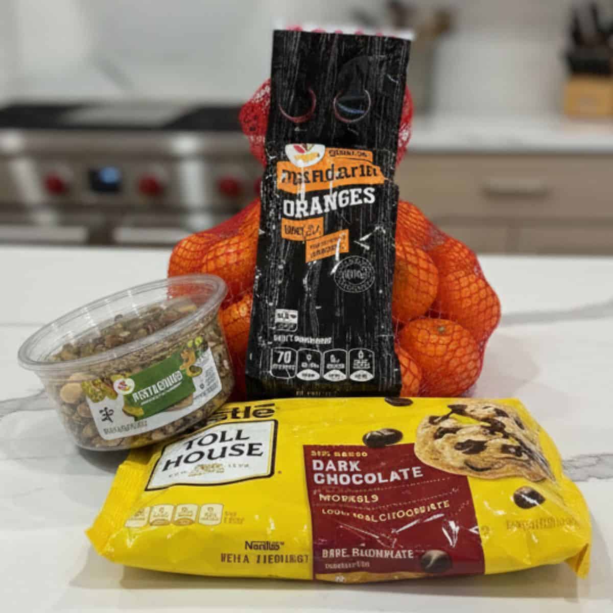A bag of clementine oranges with dark chocolate and pistachios on a kitchen counter