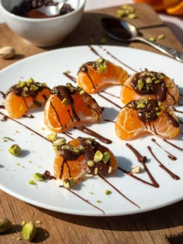 Dark chocolate drizzled pistachio mandarin oranges on a white plate