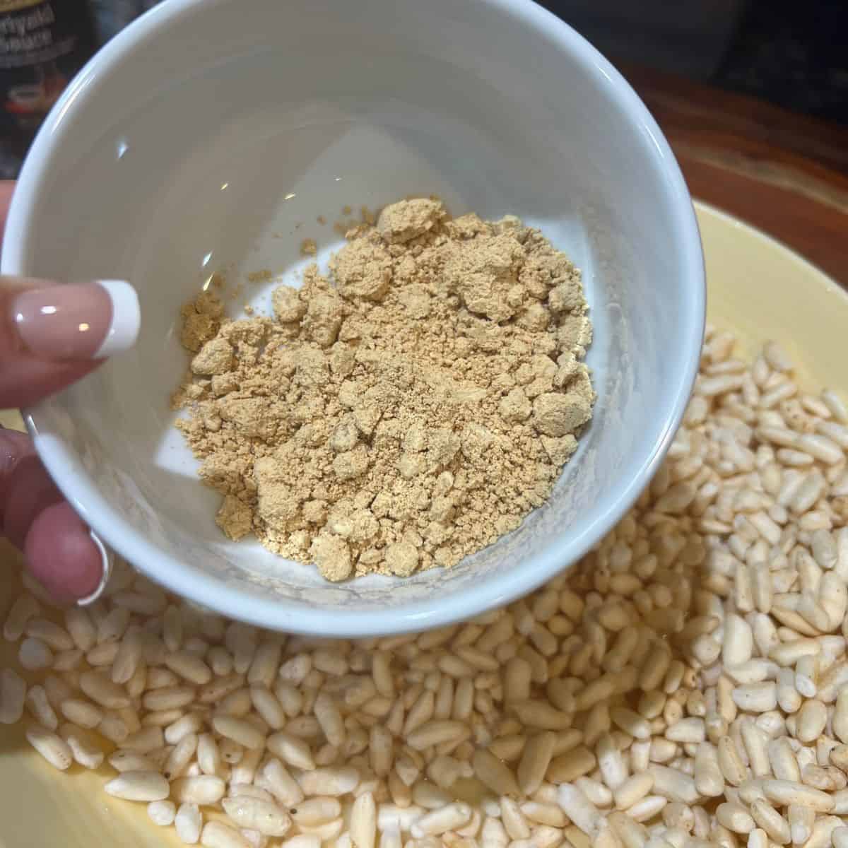 PB Fit crunch being poured into a bowl of puffed rice for Krispie treats