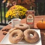 Homemade Baked Apple Cider Donuts on a white plate with yellow mums in the background