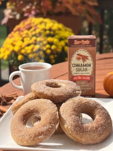 Homemade Baked Apple Cider Donuts on a white plate with yellow mums in the background