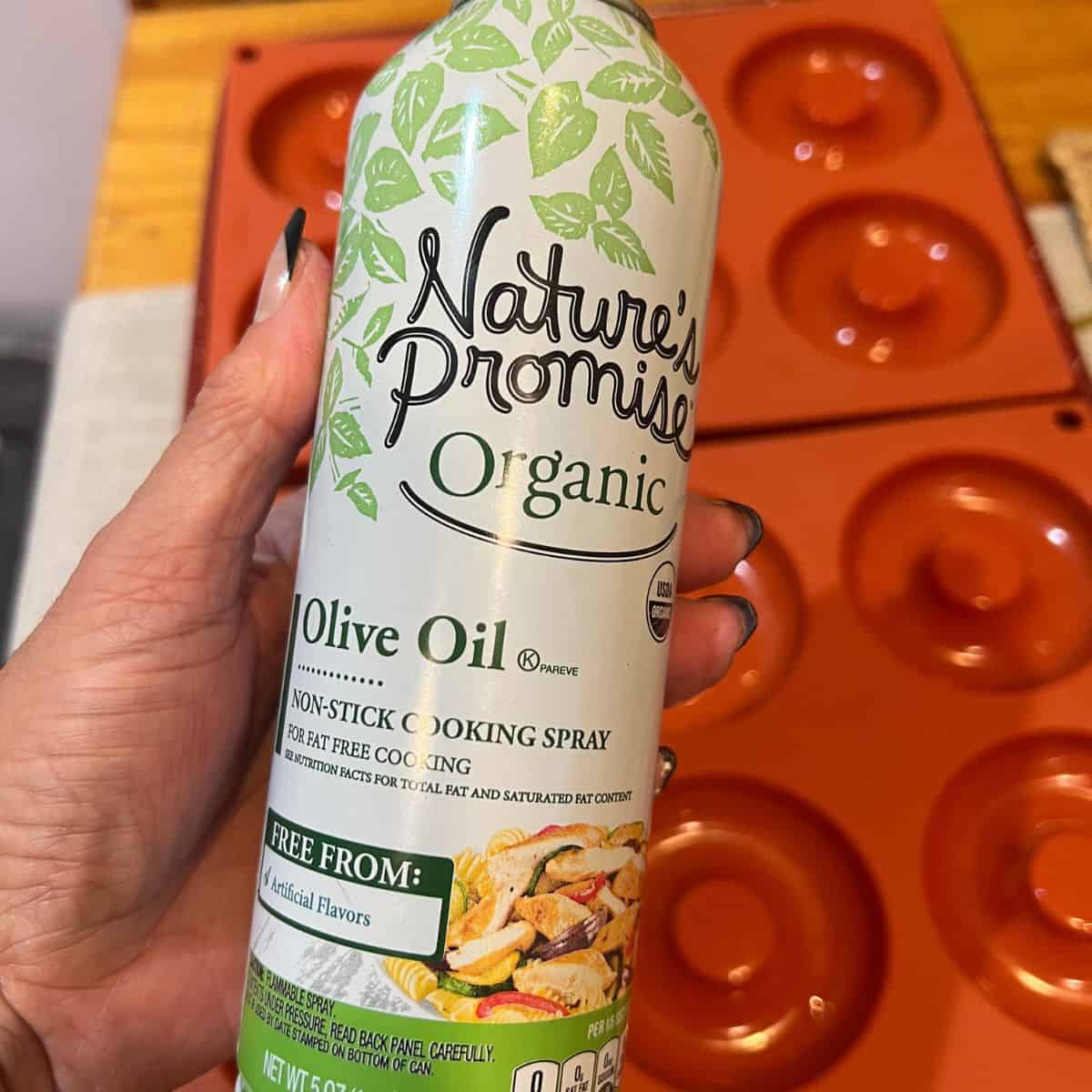 Spraying silicone donuts trays with olive oil for baked apple cider donuts recipe