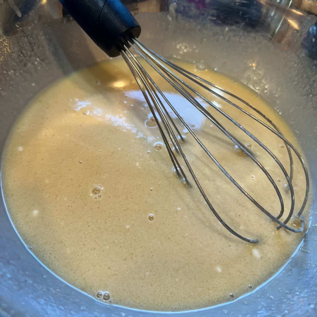 Wet donut ingredients in a bowl for baked apple cider donuts