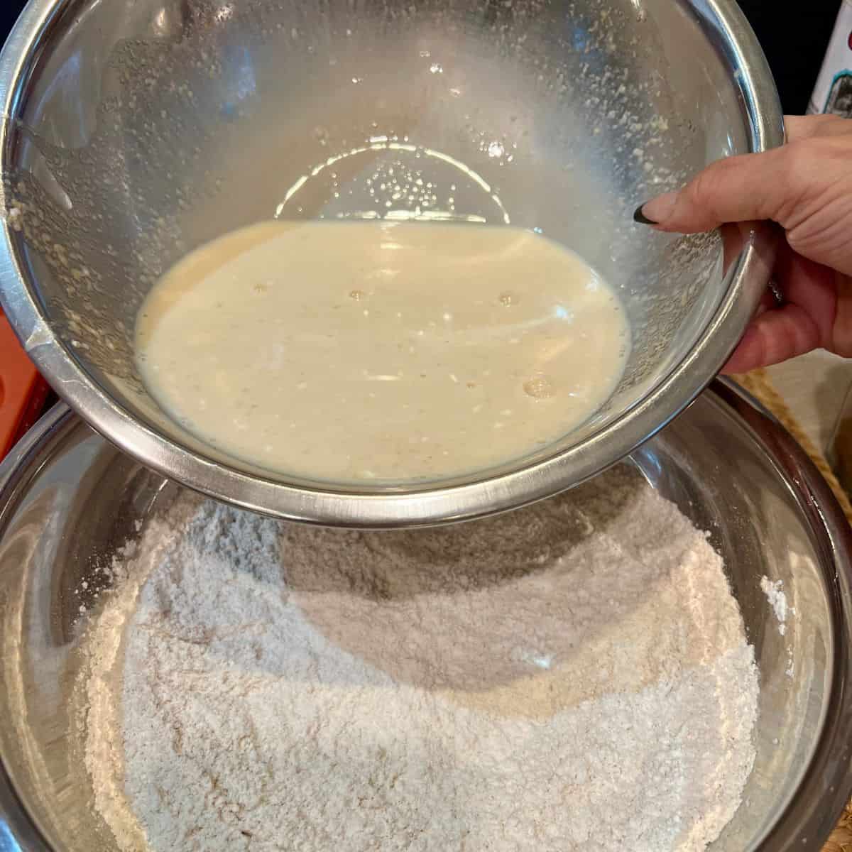 Wet apple cider donut batter being poured into dry ingredients