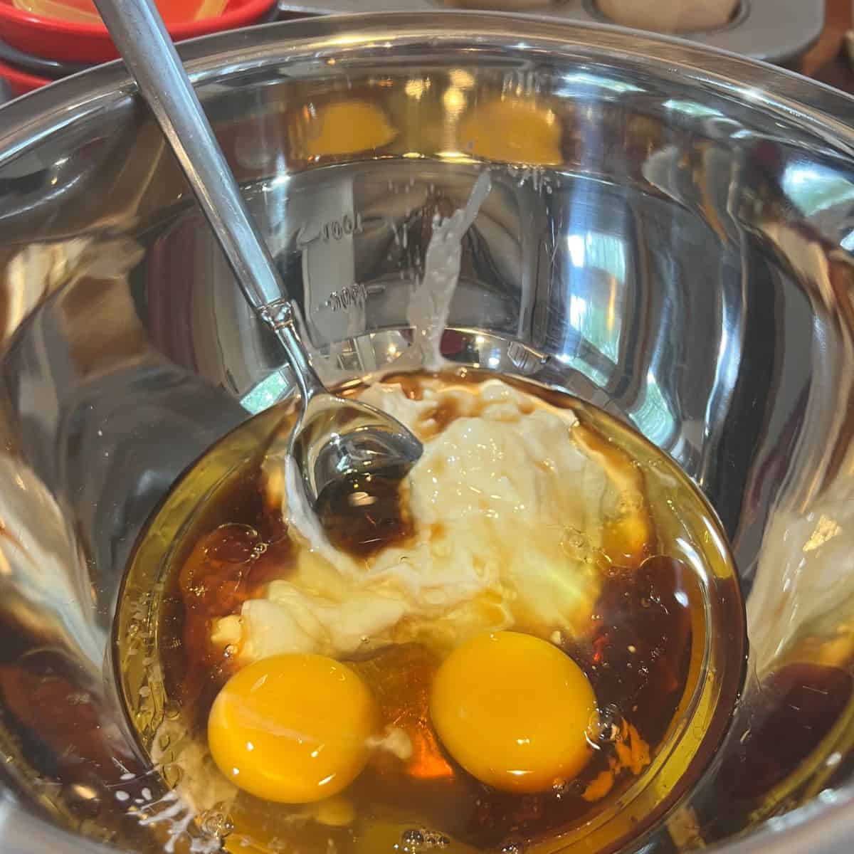 Eggs and Greek yogurt in a mixing bowl for a pear muffins recipe