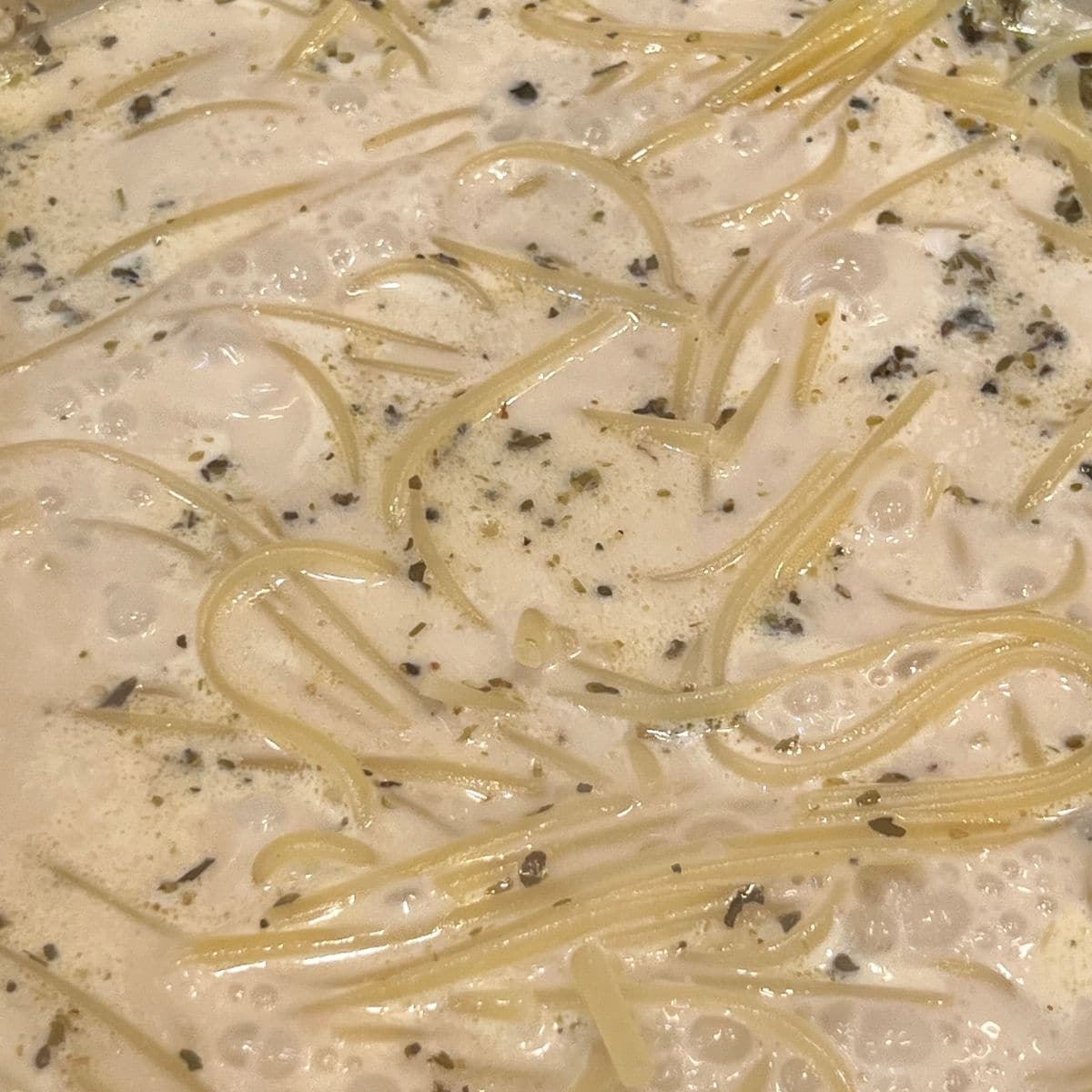 Al-dente pasta in a stockpot wit creamy garlic sauce