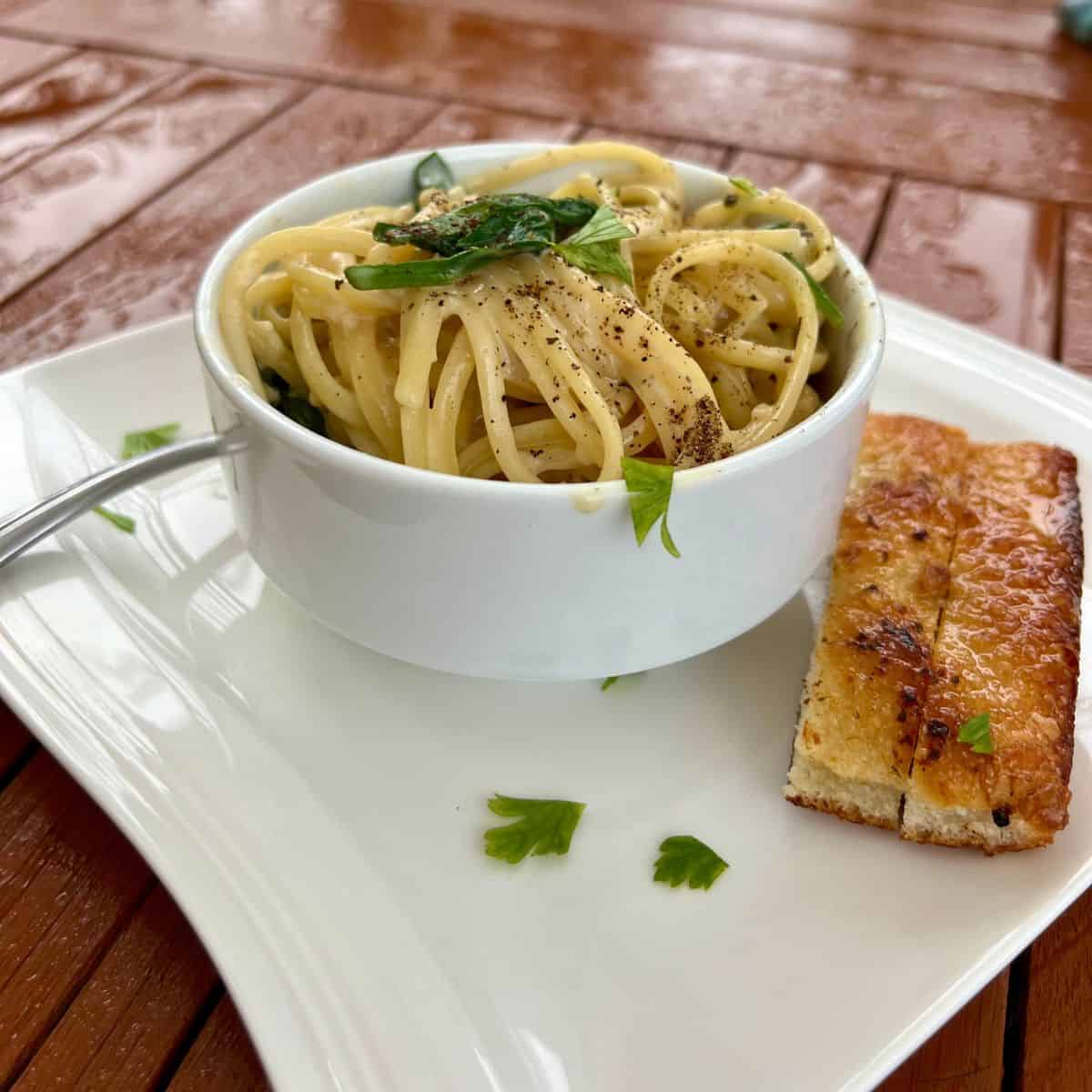 Lightened Up One Pot Creamy Garlic Pasta in a bowl on a table with bread sticks