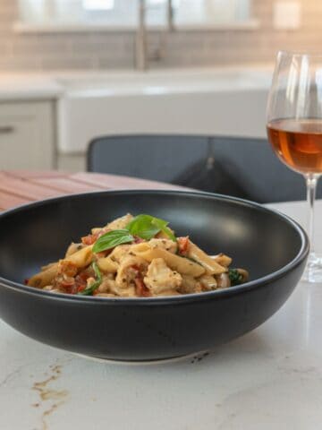 Marry Me chicken pasta in a black bowl on the kitchen counter