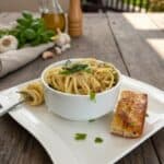 Lightend up one-pot creamy garlic pasta in a white bowl on a wooden table with breadsticks