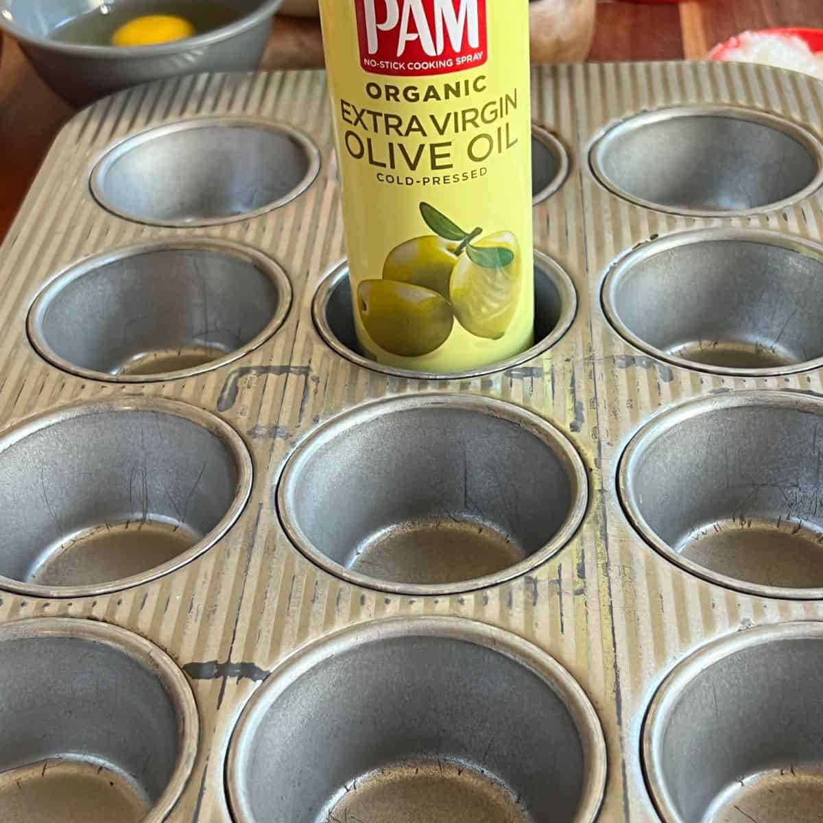 A muffin pan with a can of PAM olive oil spray for cranberry orange muffins recipe