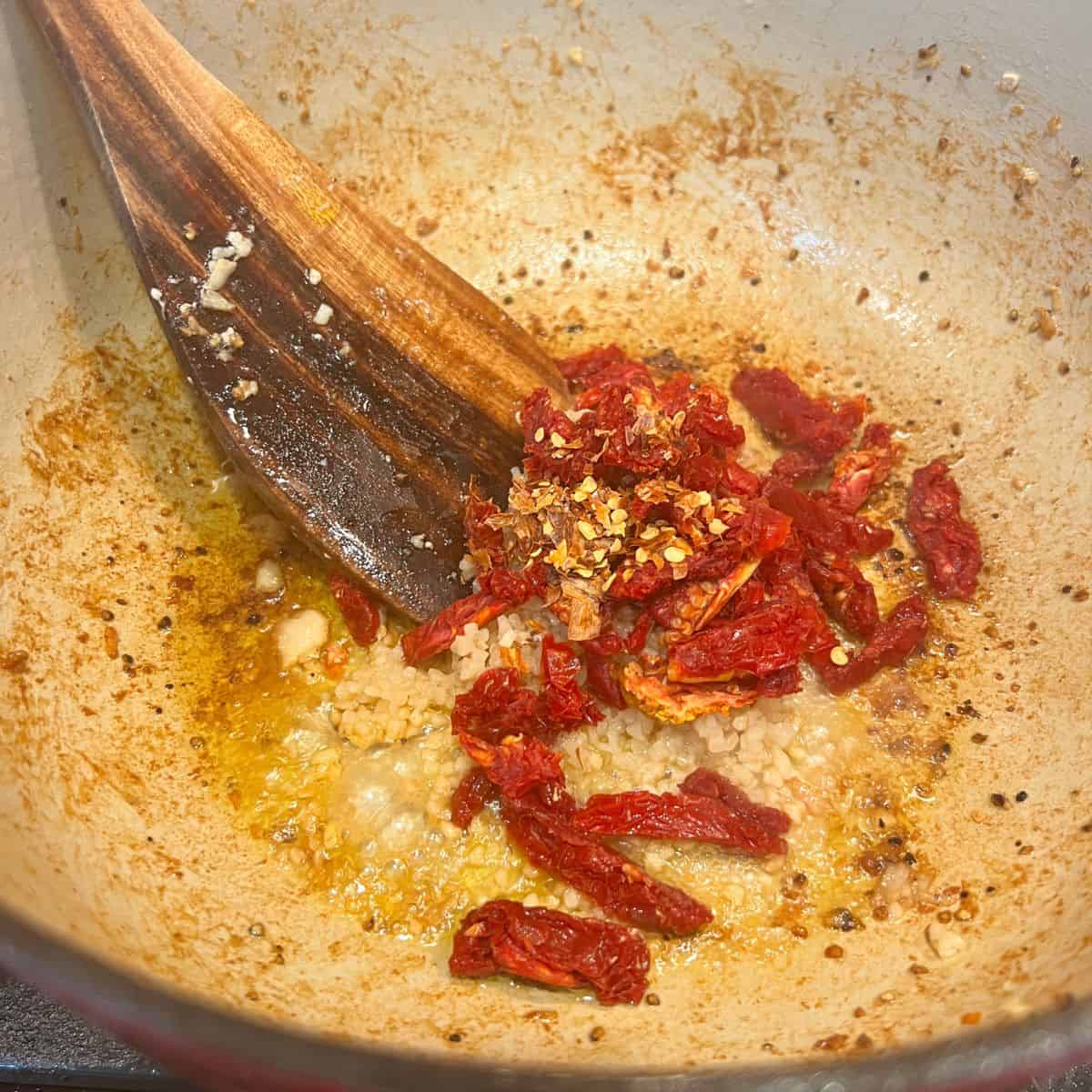 Sun dried tomatoes garlic and red pepper flakes in a stockpot