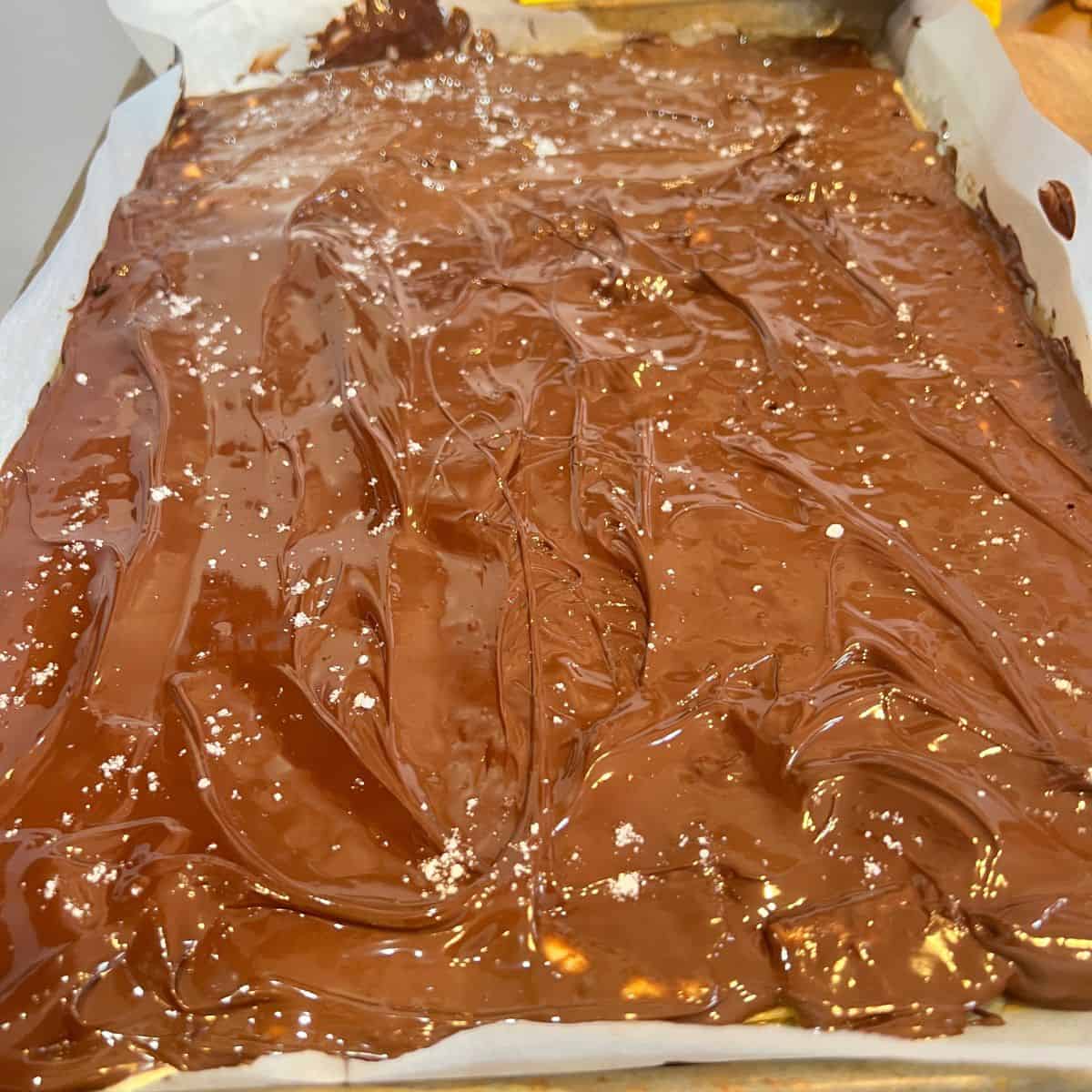 Melted chocolate over saltine covered with toffee