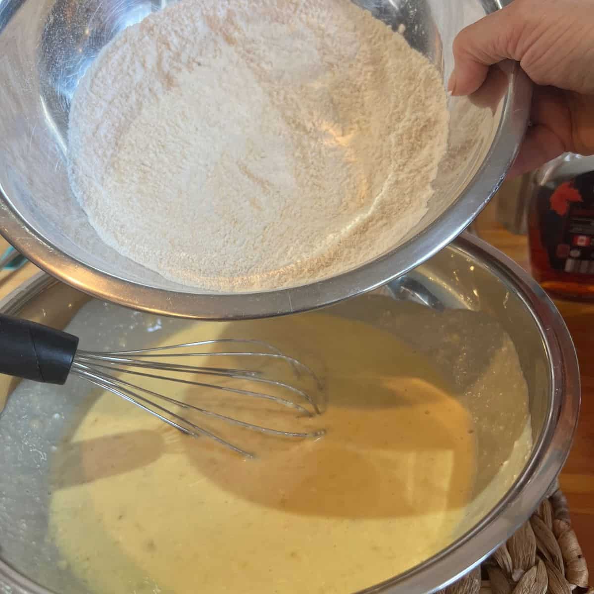 Dry ingredients being poured into wet ingredients for banana bread recipe