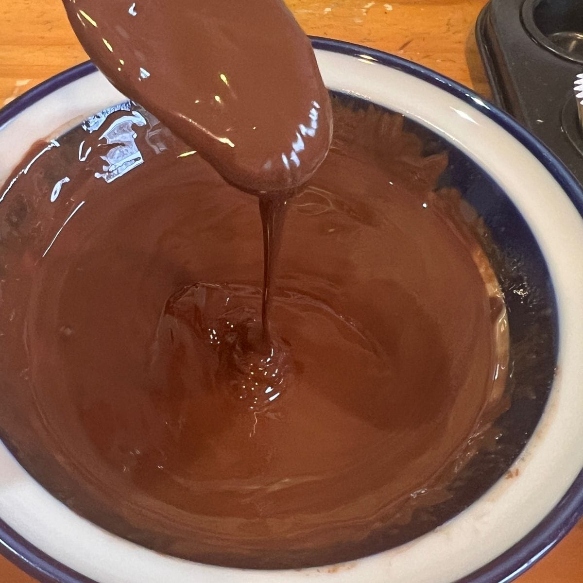 Melted chocolate in a bowl dripping off of a spoon