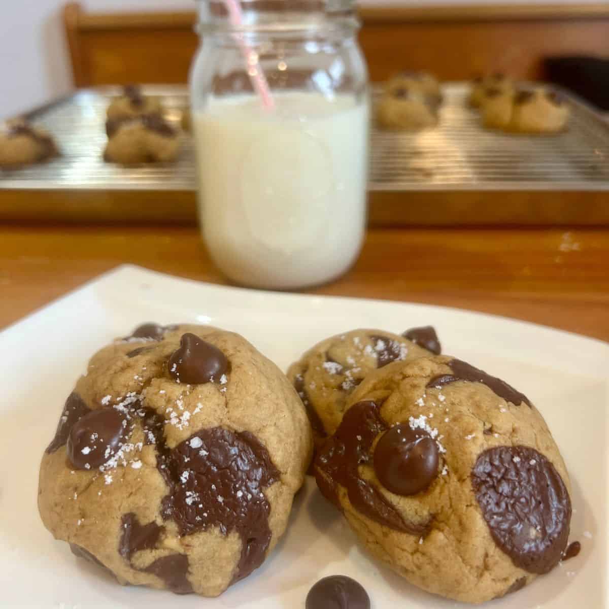 A glass of milk with soft & chewy homemade chocolate chip cookies