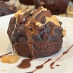 Close-up of healthy chocolate chip peanut butter muffin with melted chocolate and peanut butter drizzle on a white plate