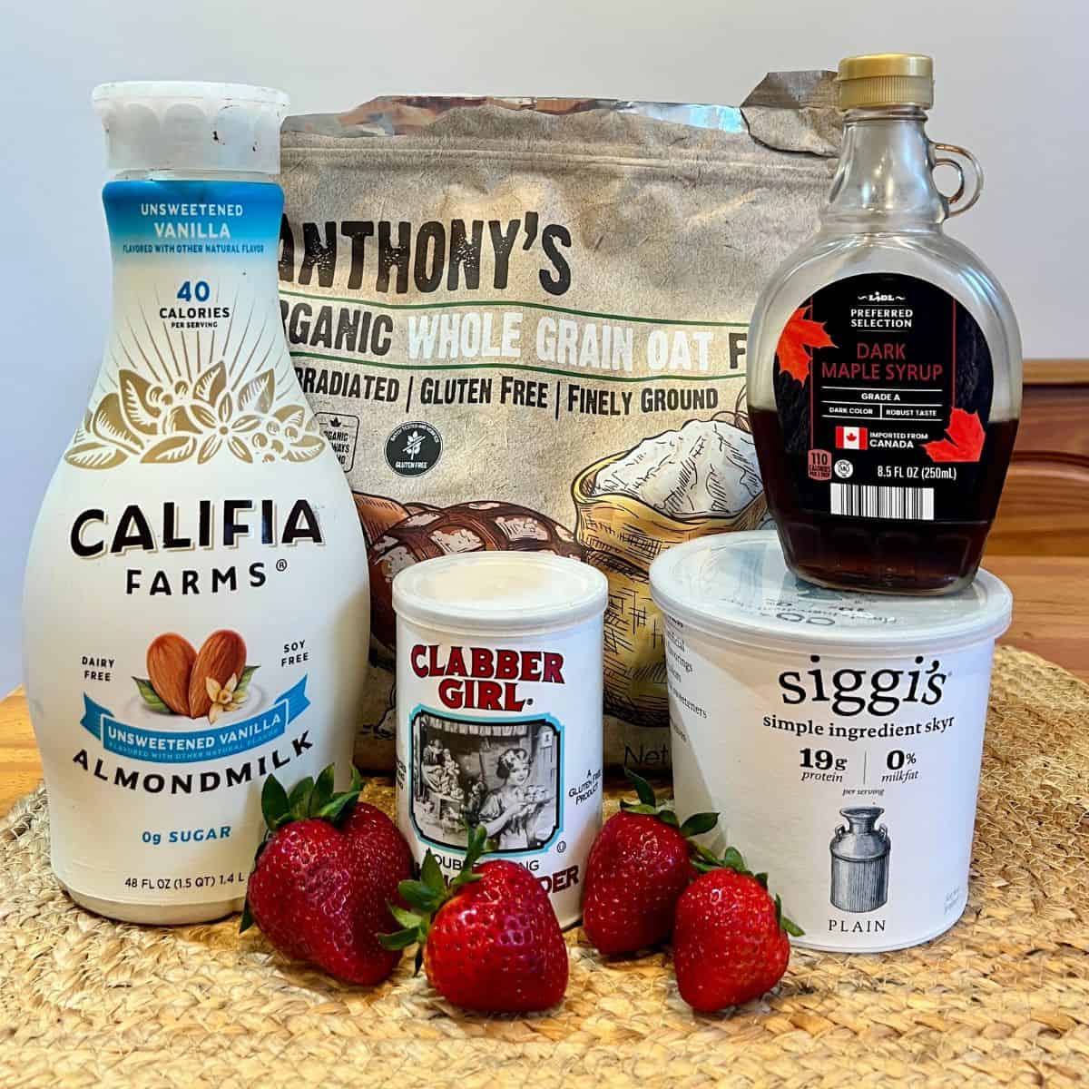 Ingredients for protein strawberry shortcake mug cake including oat flour, Greek yogurt, almond milk, maple syrup, baking powder, and fresh strawberries