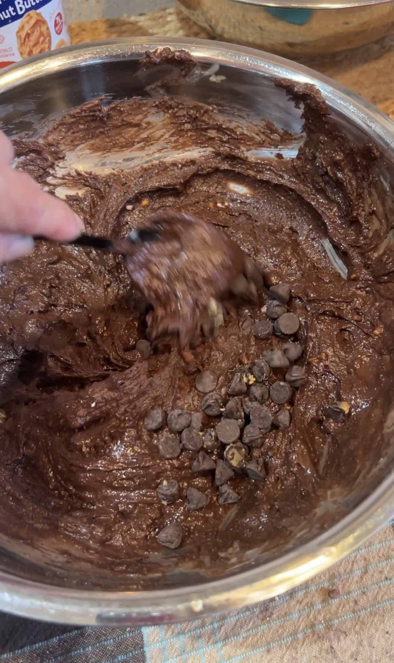 Chocolate chips being folded into chocolate peanut butter muffin batter