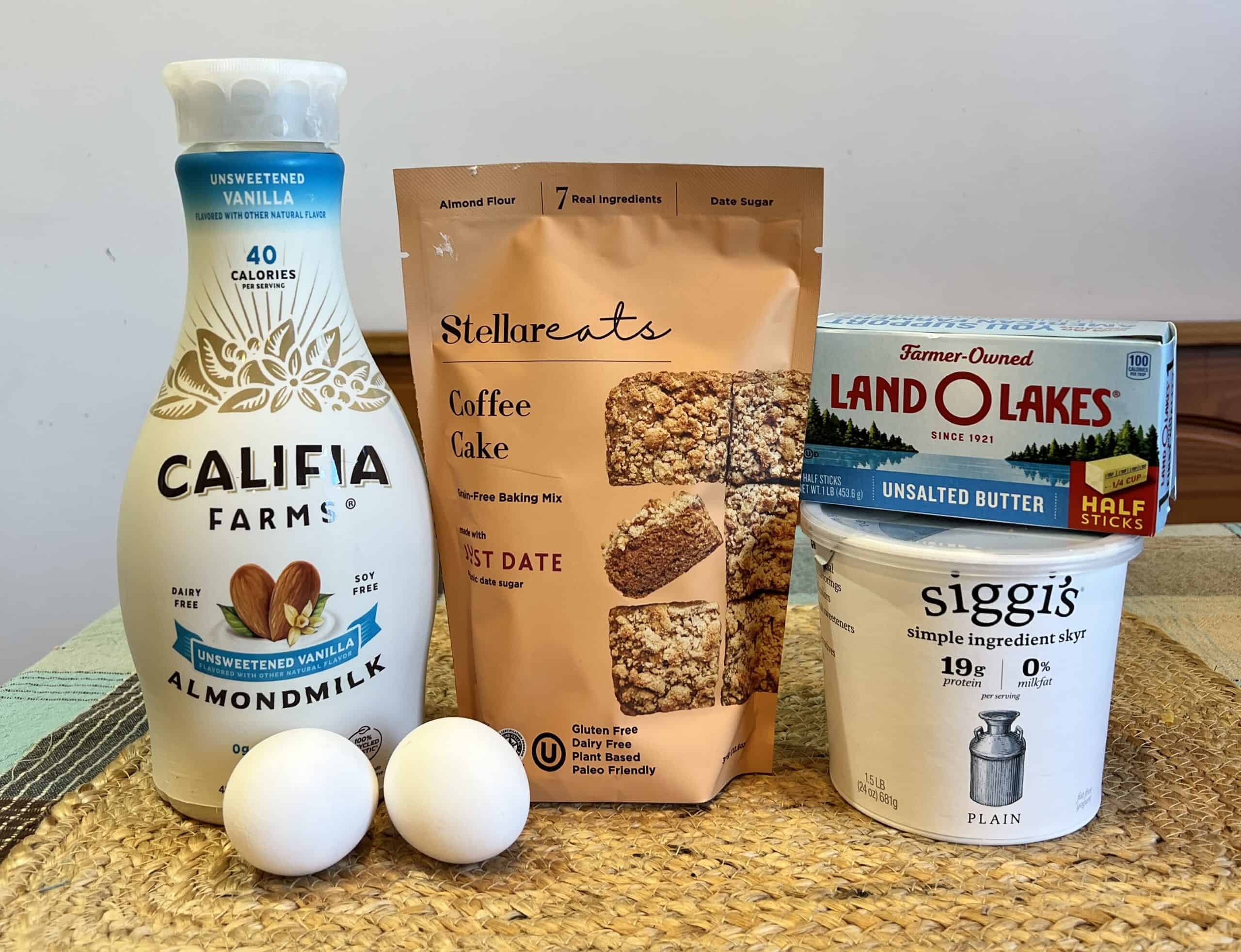 Stellareats coffee cake mix with eggs, almond milk, butter, and Greek yogurt on a table for making coffee cake muffins