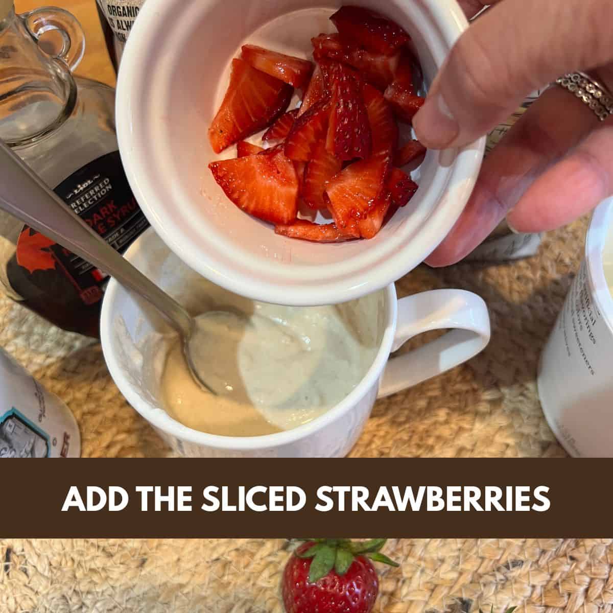Hand adding sliced strawberries into mug cake batter for strawberry shortcake mug cake