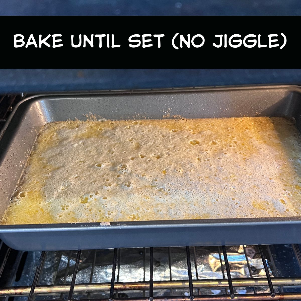 Lemon bars baking in a 13x9 pan in the oven with filling setting
