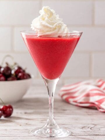 High-protein cherry Jell-O fluff made with Greek yogurt served in a martini glass and topped with whipped cream.