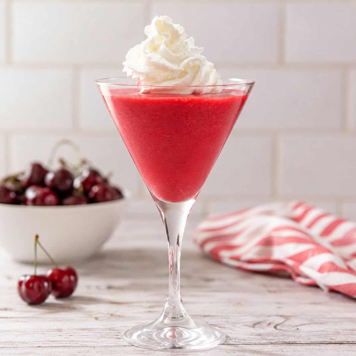High-protein cherry Jell-O fluff made with Greek yogurt served in a martini glass and topped with whipped cream.