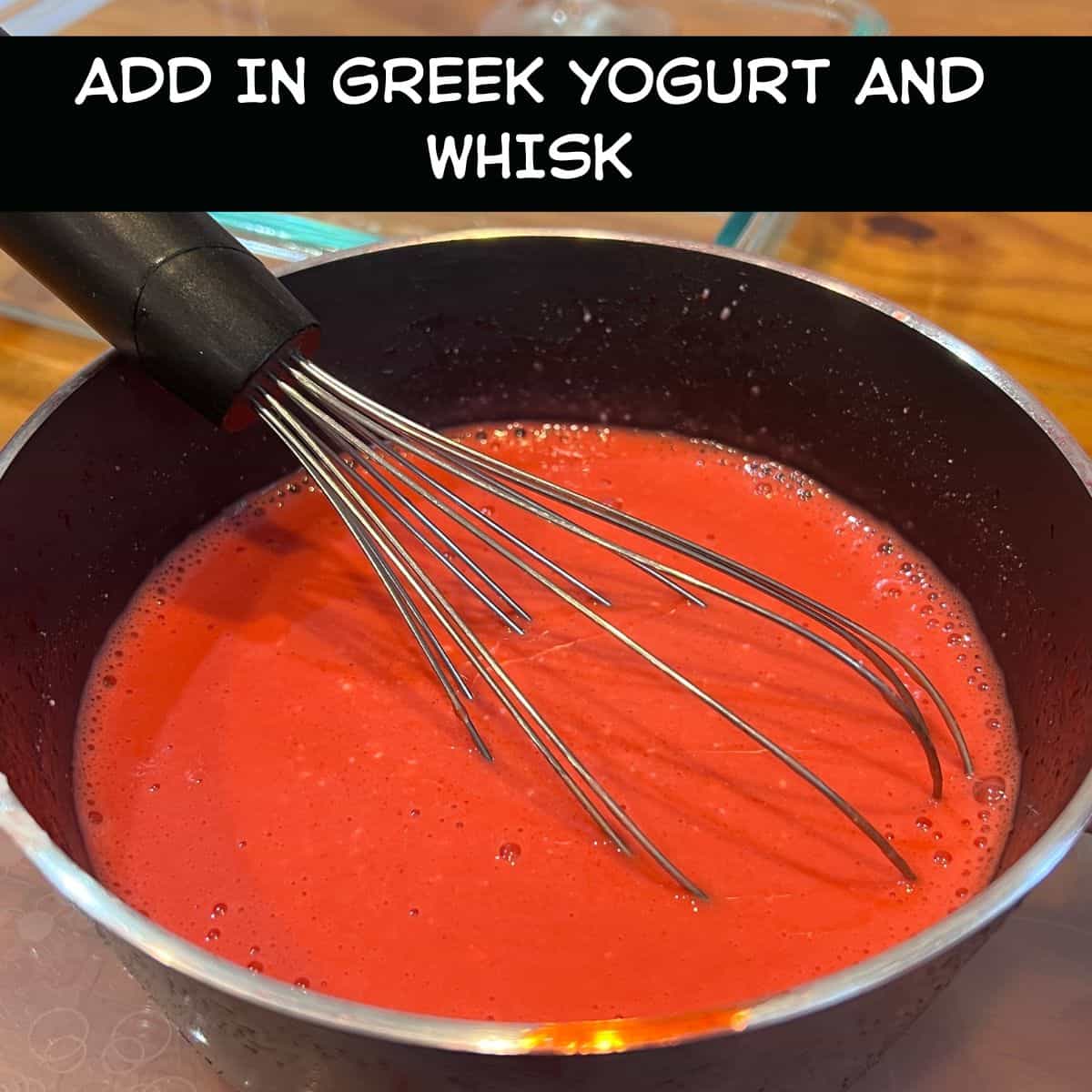 Greek yogurt being mixed into cooled cherry gelatin to make a creamy high-protein cherry Jell-O dessert.