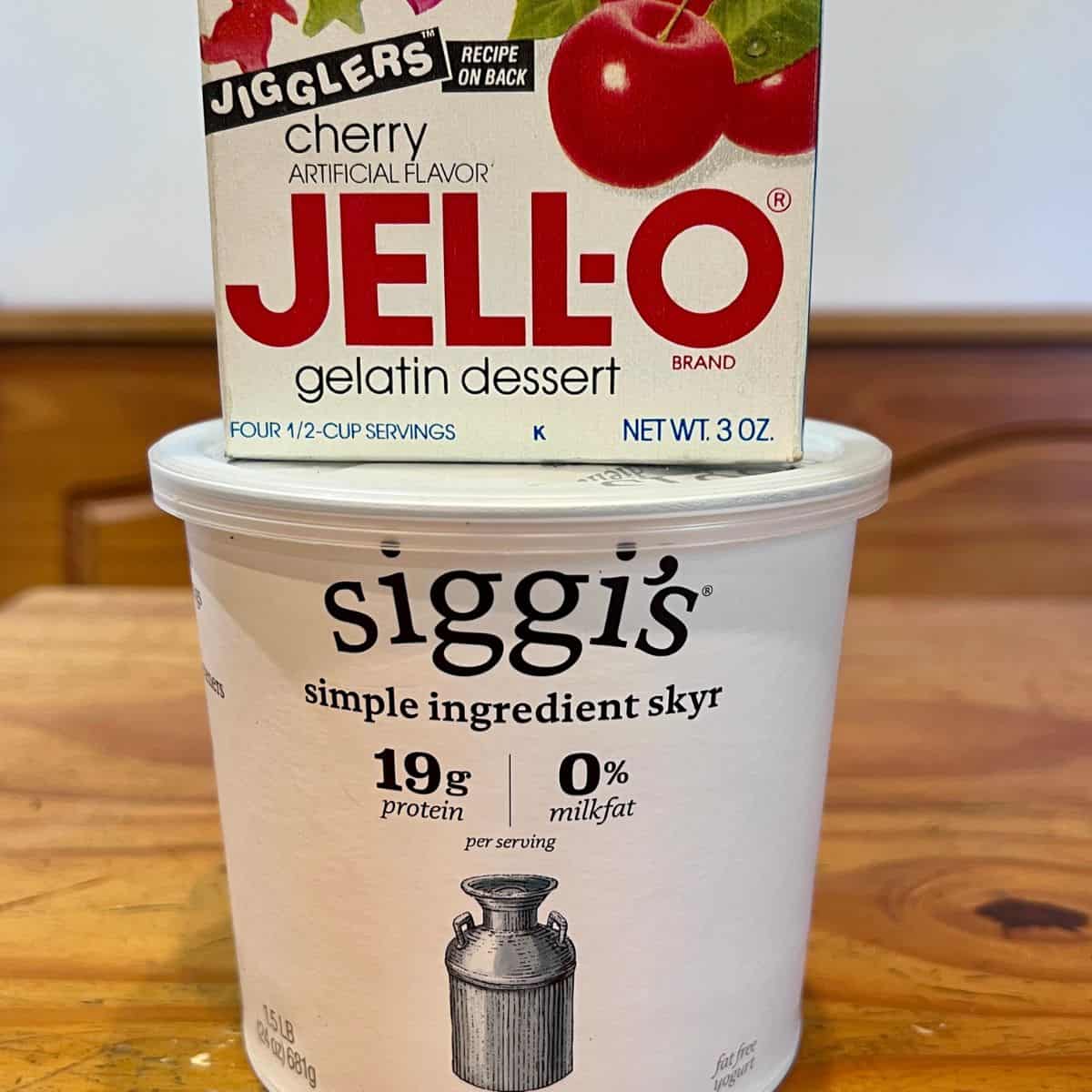 Ingredients for cherry protein Jell-O dessert including a 3-ounce box of cherry gelatin dessert mix and plain Greek yogurt.