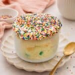 Healthy Funfetti dot cake jar topped with rainbow nonpareil sprinkles and creamy frosting in a glass jar.