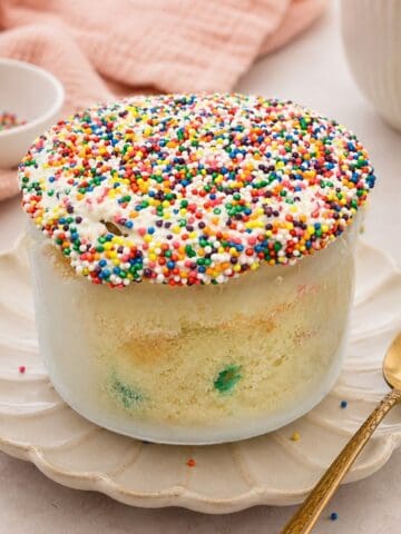 Healthy Funfetti dot cake jar topped with rainbow nonpareil sprinkles and creamy frosting in a glass jar.
