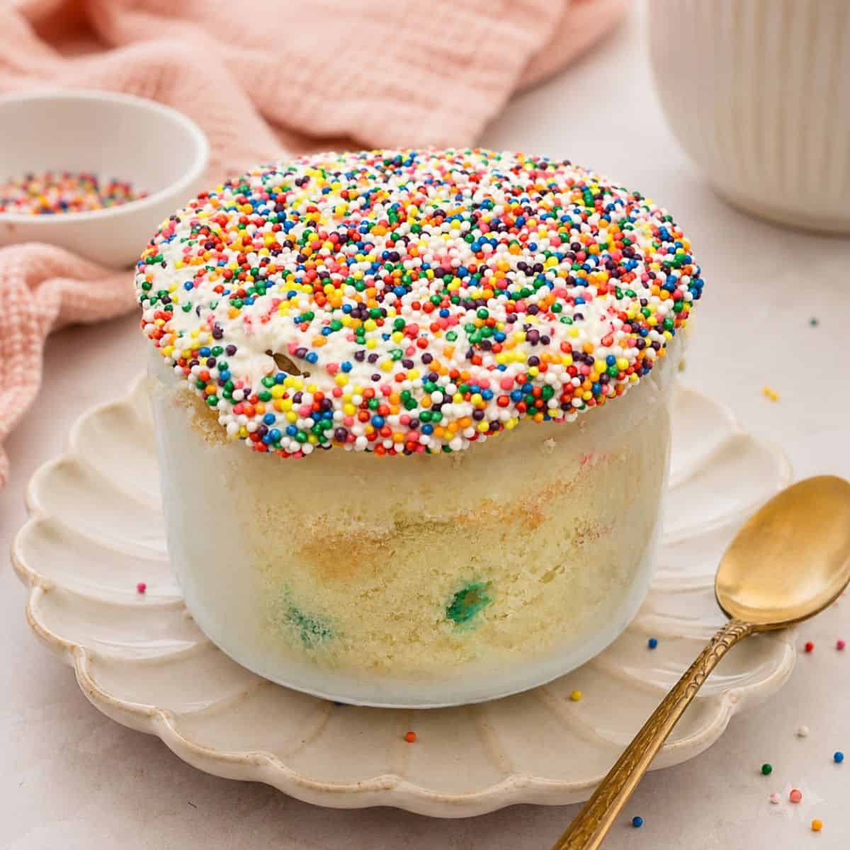 Healthy Funfetti dot cake jar topped with rainbow nonpareil sprinkles and creamy frosting in a glass jar.