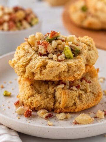 Close-up of two keto almond flour butter cookies topped with crushed pecans on a white plate.