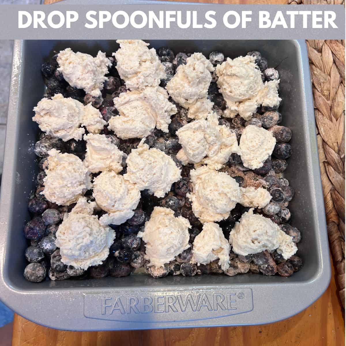 Dollops of homemade cobbler batter spooned evenly over the blueberry filling in an 8x8-inch baking dish before baking an Easy 5-Ingredient Shortcut Blueberry Cobbler.