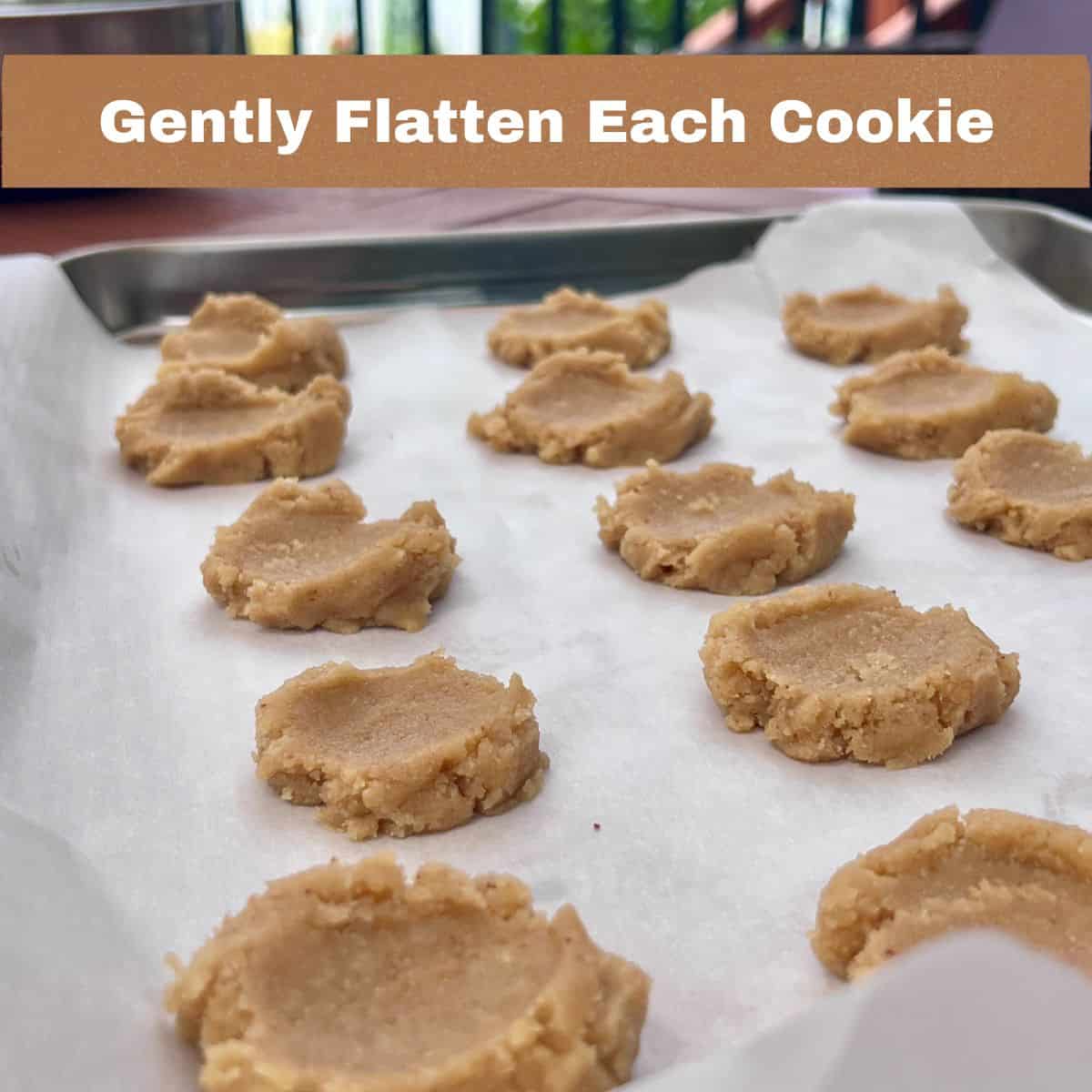 Flattened almond flour butter cookie dough on a parchment-lined baking sheet before baking