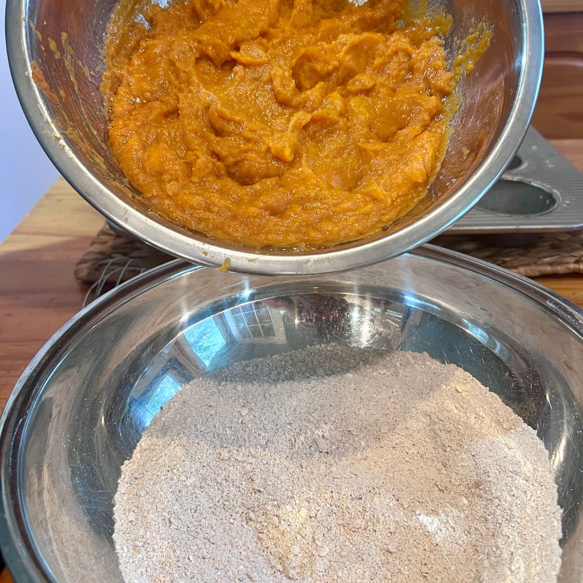 Wet pumpkin mixture being poured into the dry oat flour ingredients