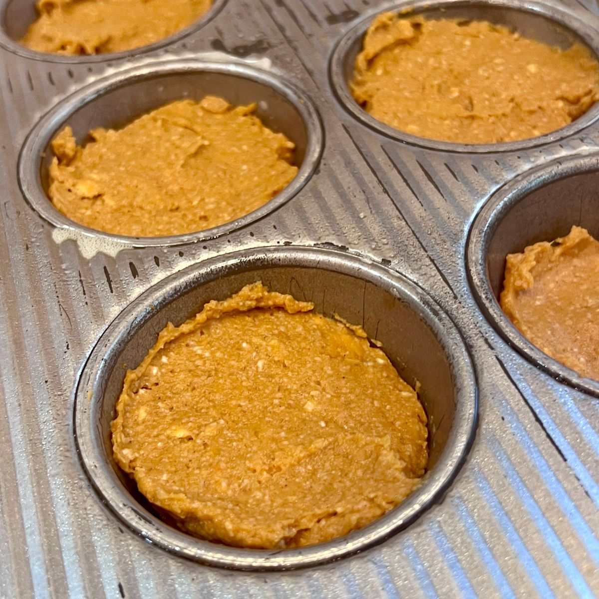 Pumpkin sweet potato muffin batter divided evenly in a muffin pan