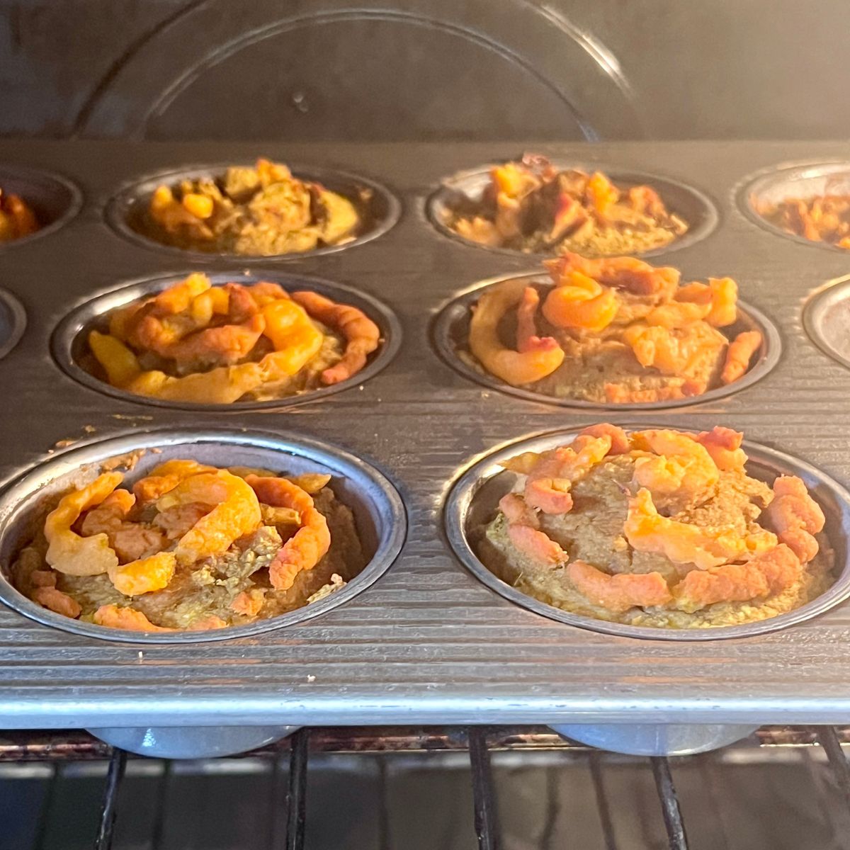 Pumpkin sweet potato muffins baking in a muffin tin in the oven
