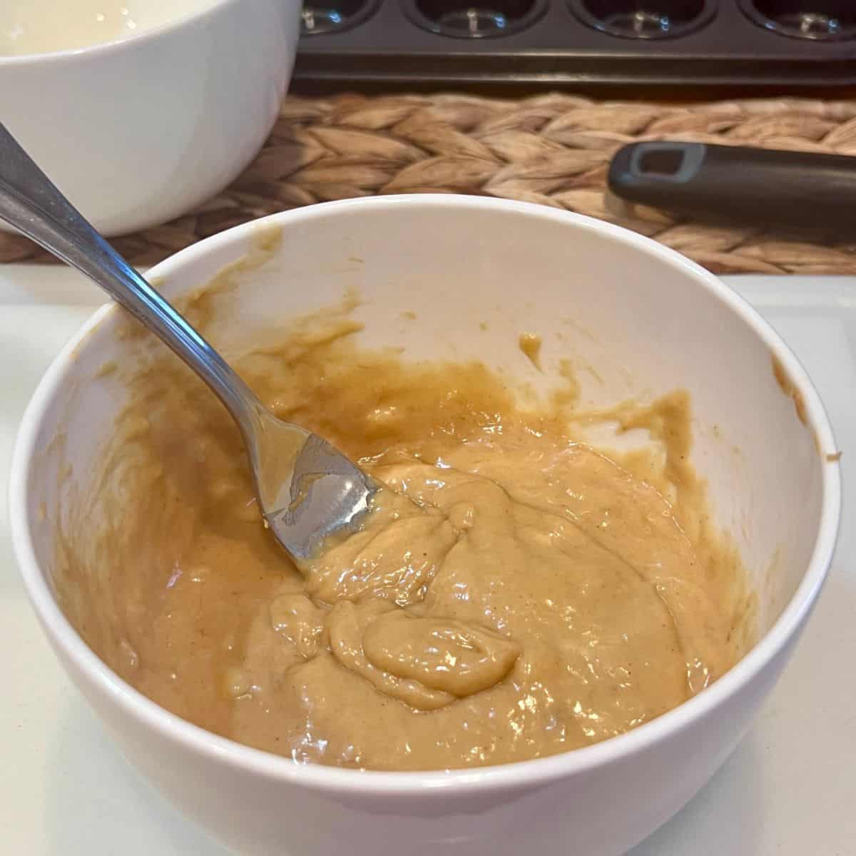 Bowl of mixed banana, egg, and creamy peanut butter batter for homemade 3-ingredient flourless mini muffins.