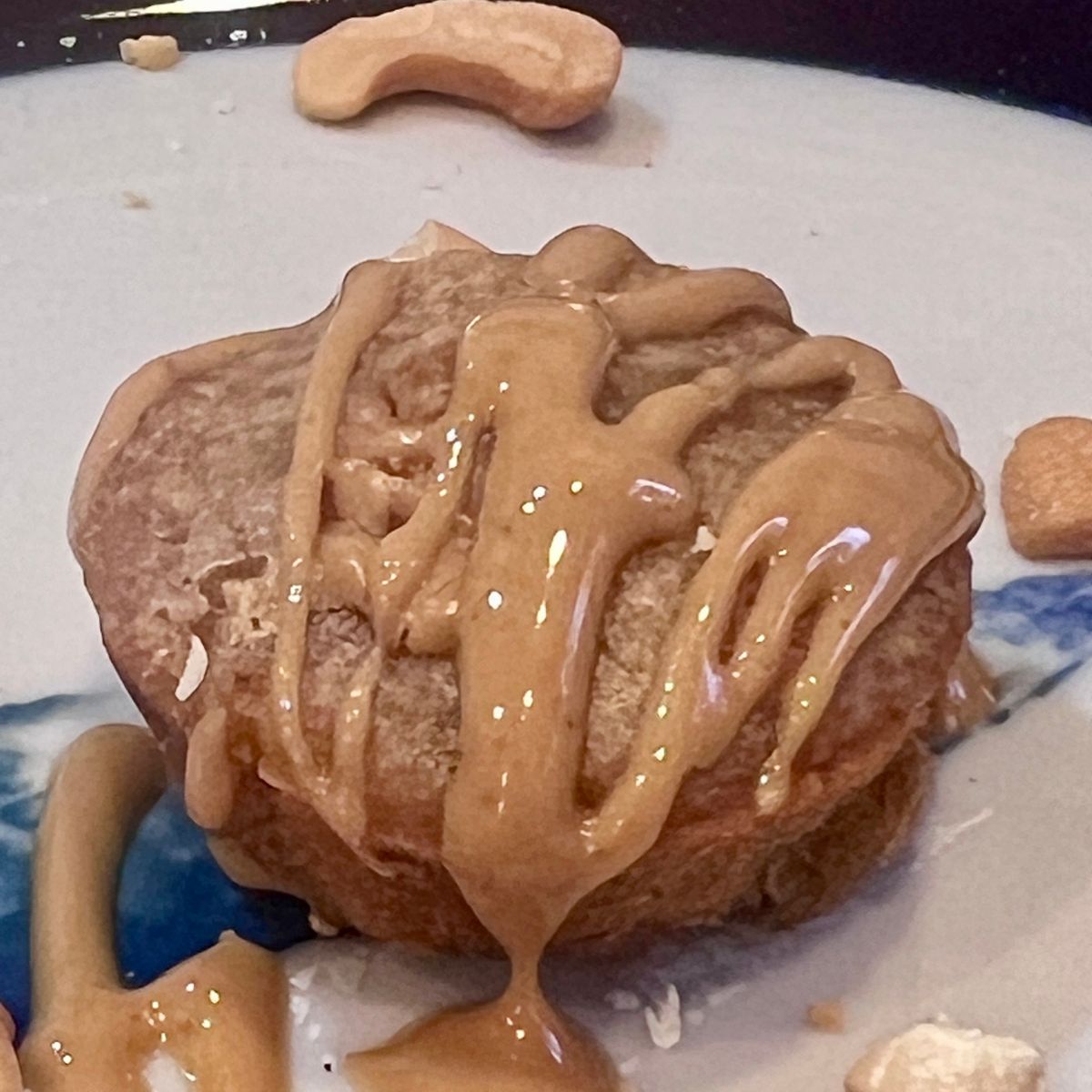 Close-up of a homemade 3-ingredient peanut butter banana mini muffin topped with creamy peanut butter drizzle.