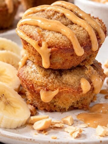 Two stacked 3-ingredient peanut butter banana mini muffins topped with creamy peanut butter drizzle.