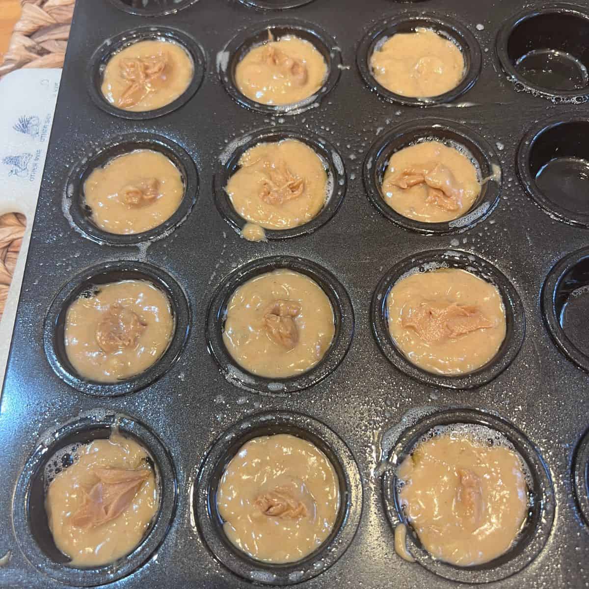 Mini muffin pan filled with peanut butter banana batter made from mashed banana, egg, and creamy peanut butter, ready for baking.